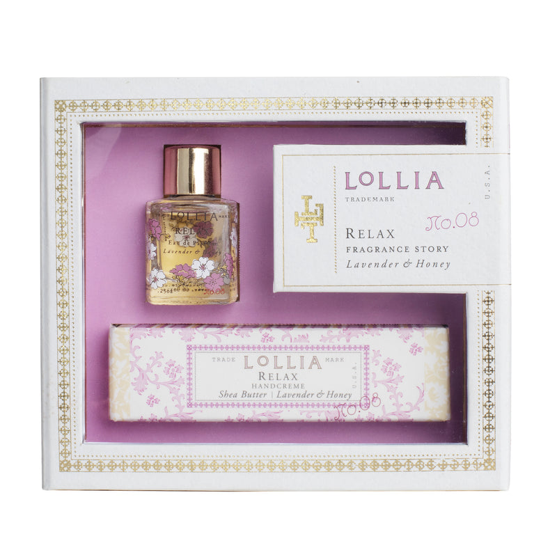 The Lollia Relax Fragrance Story Gift Set by Margot Elena, themed in purple and white, includes a small bottle of Eau de Parfum, a tube of hand cream, and a card. Each item is branded with "Lollia" and labeled "Relax" and "Lavender & Honey." The set is presented in a white box with ornate gold accents and a clear viewing window.