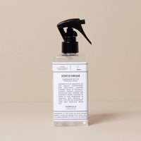 A clear spray bottle of Norfolk Natural Living Rose Garden Scented Vinegar sits on a neutral surface. This vegan, eco-friendly cleaner by Norfolk Natural Living is ideal for surfaces and glass, leaving a fresh rose garden fragrance.