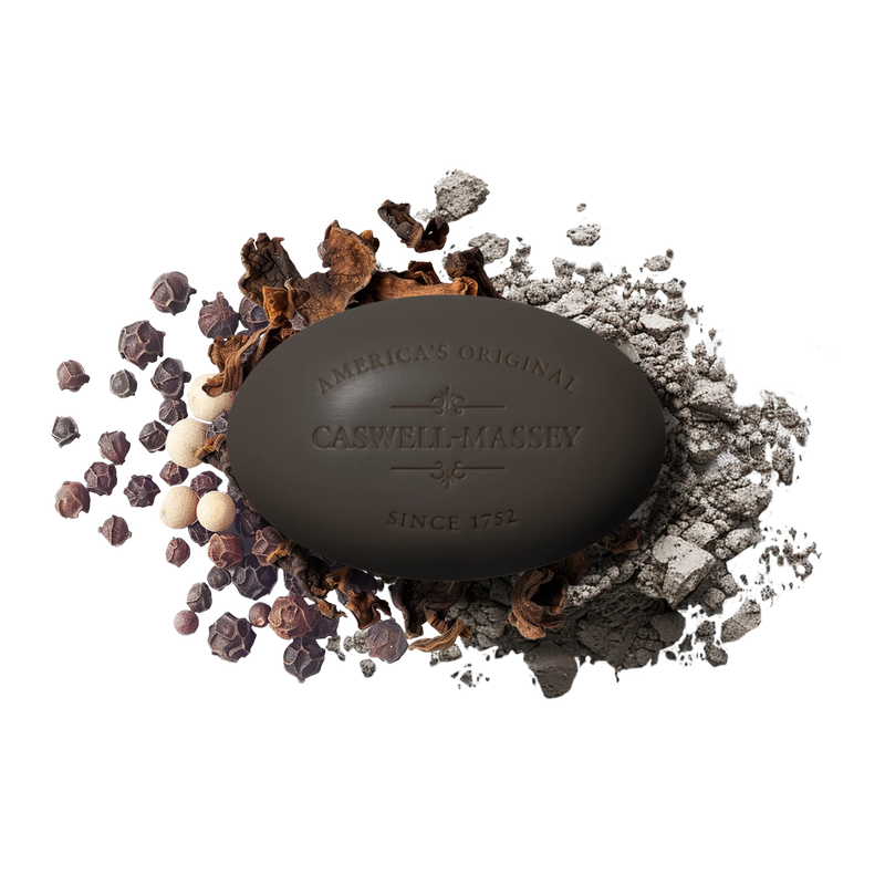 A dark Caswell-Massey Oaire Bar Soap, embossed with "America's Original Caswell-Massey Since 1752," rests on scattered peppercorns and spices, adding natural elegance to your daily ritual.