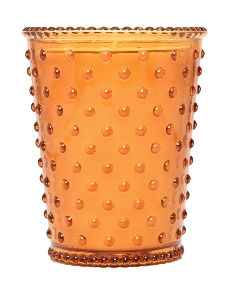 The Simpatico NO. 28 Pumpkin & Clove Hobnail Glass Candle features an orange, raised dot pattern glass with a flared rim and beaded edge—ideal for use as a soy candle or as autumn-inspired décor.
