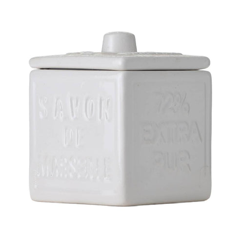 A square, white ceramic cotton ball holder with a cover from FRENCH SOAPS, featuring embossed text that says "SAVON DE MARSEILLE" and "72% EXTRA PUR" on the sides. The cover includes a small, rounded handle on top, inspired by the essence of Provence.