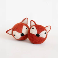 The MODERNBEAST Fox Beastball Wool Cat and Dog Toy features two handmade, round felt balls resembling fox faces in orange and white, complete with pointy ears and black noses, crafted from natural wool by MODERNBEAST.