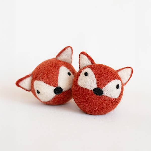 The MODERNBEAST Fox Beastball Wool Cat and Dog Toy features two handmade, round felt balls resembling fox faces in orange and white, complete with pointy ears and black noses, crafted from natural wool by MODERNBEAST.