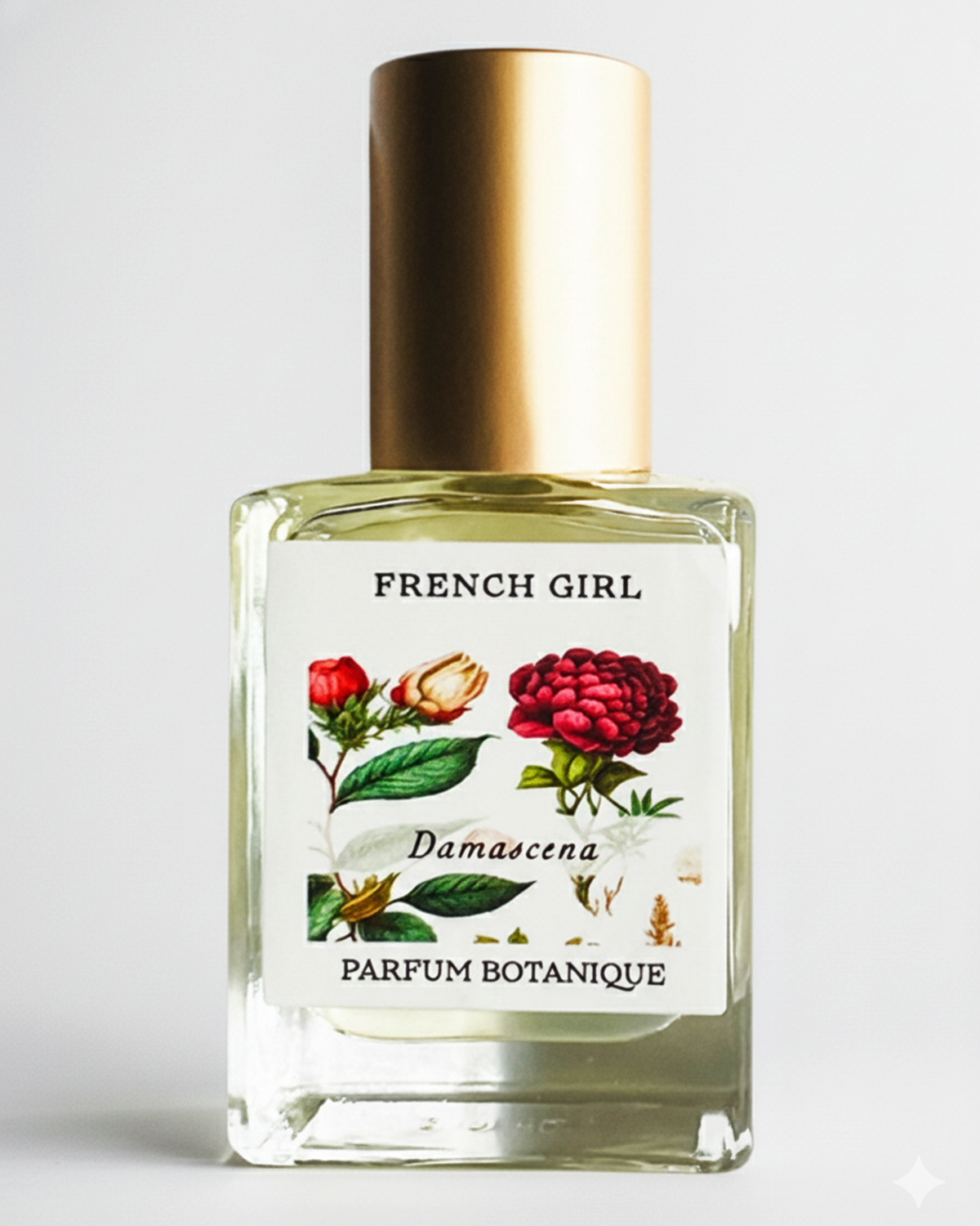 A clear glass perfume bottle with a gold cap, labeled "FRENCH GIRL Damascena Rose Organic Vegan Natural Aromatherapy Perfume," features floral artwork and contains an alcohol-free fragrance made from natural essential oils.