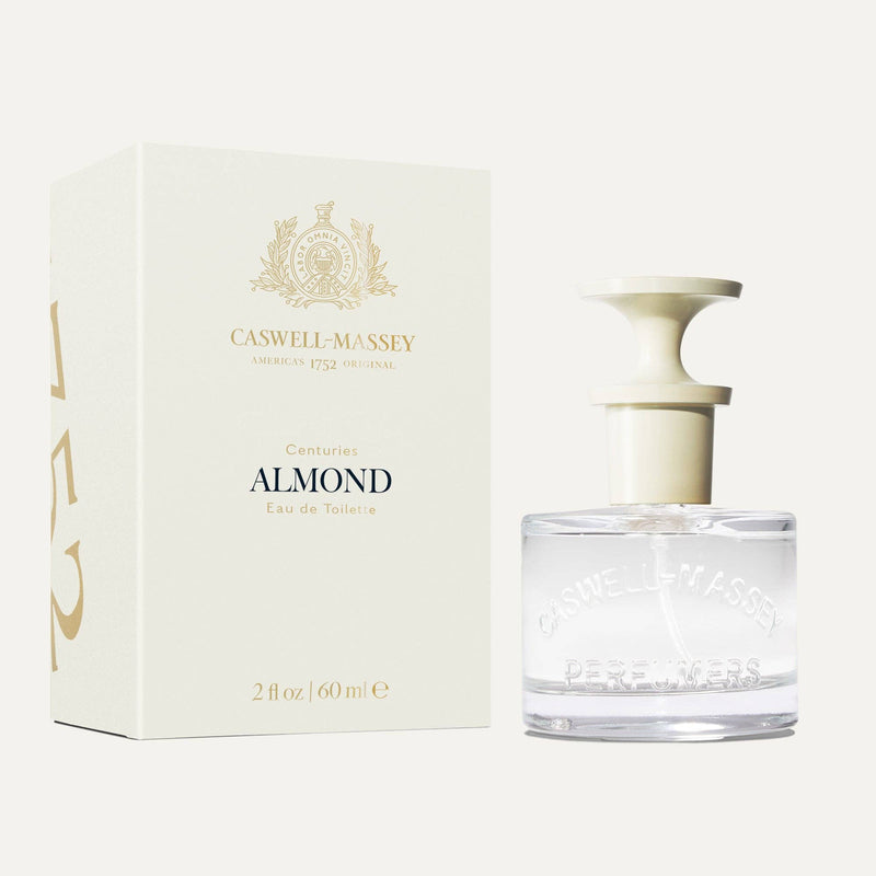 A clear glass bottle of Caswell-Massey Almond Eau de Toilette 60mL with a white cap is shown beside its cream-colored box with gold accents—a classic fragrance from Caswell-Massey.