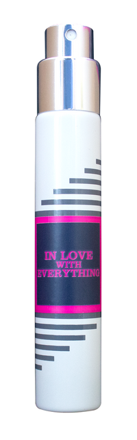 A white cylindrical spray bottle features a metallic nozzle and cap, adorned with black and grey striped accents. It showcases a pink-bordered black label reading "In Love With Everything" from Imaginary Authors. This travel-size fragrance delivers an energizing scent perfect for everyone, making it the ultimate gender-neutral perfume.