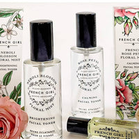 A FRENCH GIRL Organic Floral Face Mist Hydrating Toner in French Rose stands upright with floral packaging, next to a small green organic skincare oil bottle lying on its side.