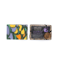 Two artisan soap bars from Three Sisters Apothecary. The left bar has purple, yellow, and blue swirls. The right bar, from the Three Sisters Apothecary Intensions Bar Soap line, is wrapped in a black and brown label with the text "Three Sisters Apothecary" and "Lucid Dreaming," featuring a wax seal; it is perfect for inducing deep sleep and enhancing psychic abilities.