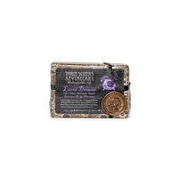 A bar of soap labeled "Three Sisters Apothecary Intensions Bar Soap - Lucid Dreaming" is shown. The wrapper features a dark, intricate design with the product name "Lucid Dreams" in the center. A round emblem with a mermaid illustration is affixed to the bottom right corner, evoking an aura of deep sleep and enhancing psychic abilities.