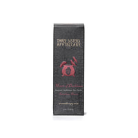 A gray box with intricate patterns, labeled "Three Sisters Apothecary," displays the product name "Intentions Aromatherapy Mist - Heart of Darkness" in red text. It highlights compassionate essential oils like Rosewood, Sandalwood, and Bourbon Vanilla. This 4 oz aromatherapy mist is a Heart of Darkness blend promoting love.