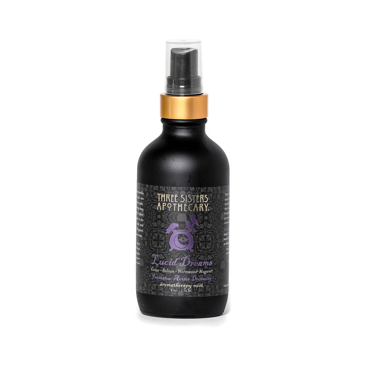 A bottle of "Three Sisters Apothecary Intentions Aromatherapy Mist - Lucid Dreaming" is shown. The bottle is matte black with a gold top and sprayer. The label features a purple design and text indicating it is a sleep-aid product containing essential oils, including soothing Cedarwood and other botanicals.