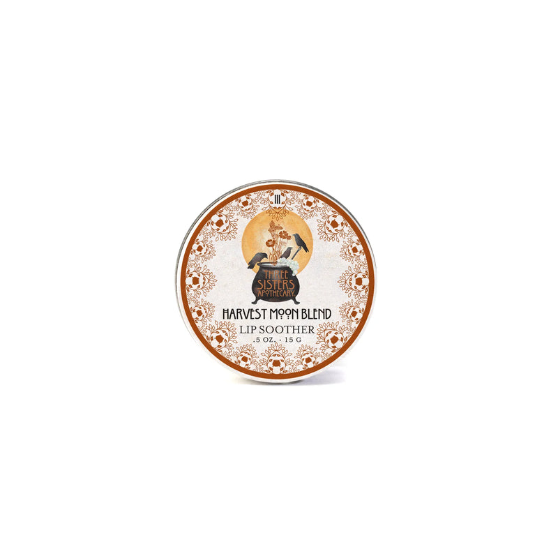 A round tin of Three Sisters Apothecary Harvest Moon Lip Soother, featuring a vintage illustration of a woman and orange floral borders, labeled with the brand Three Sisters Apothecary.