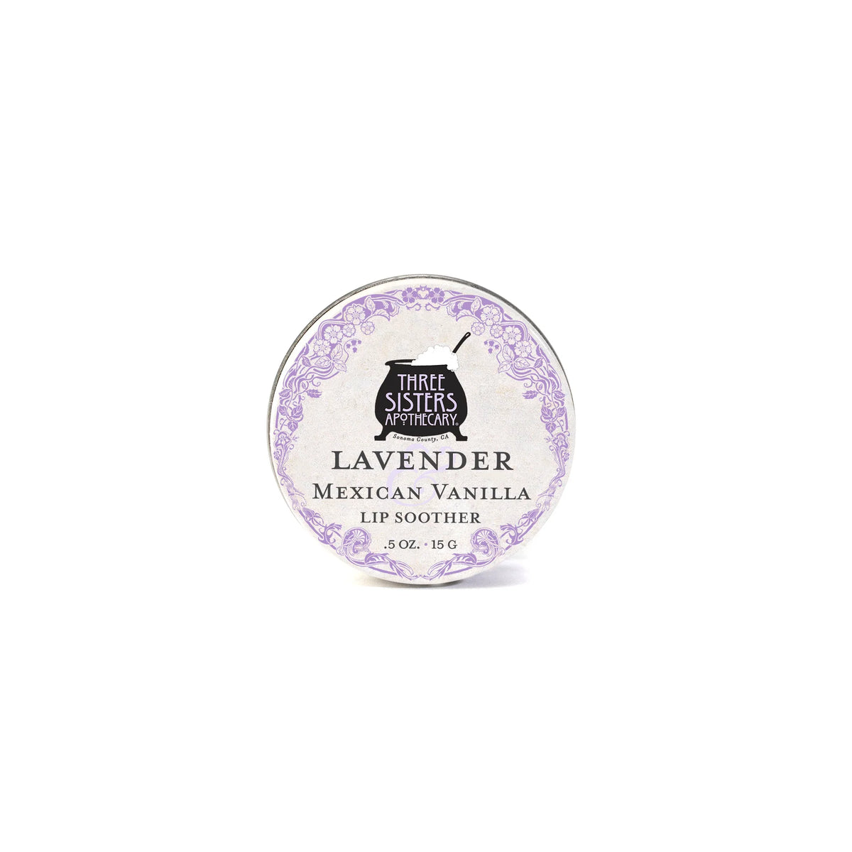 A round tin of Three Sisters Apothecary Lavender & Mexican Vanilla Lip Soother, a natural beeswax lip balm (0.5 oz/15g), features a decorative purple border and text on a white background.