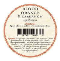 Round label for Three Sisters Apothecary Blood Orange & Cardamon Lip Shimmer hydrating balm, directions to apply often, barcode, and ingredients: natural beeswax, oils, butters, essential oils. Red/black text on cream background.