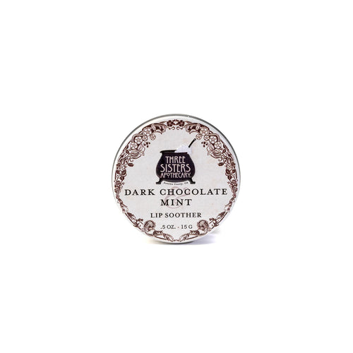 A 0.5 oz (15 g) round tin of Three Sisters Apothecary Dark Chocolate & Mint Lip Soother, with brown edging and vintage label, uses natural ingredients to moisturize lips; shown on a white background.