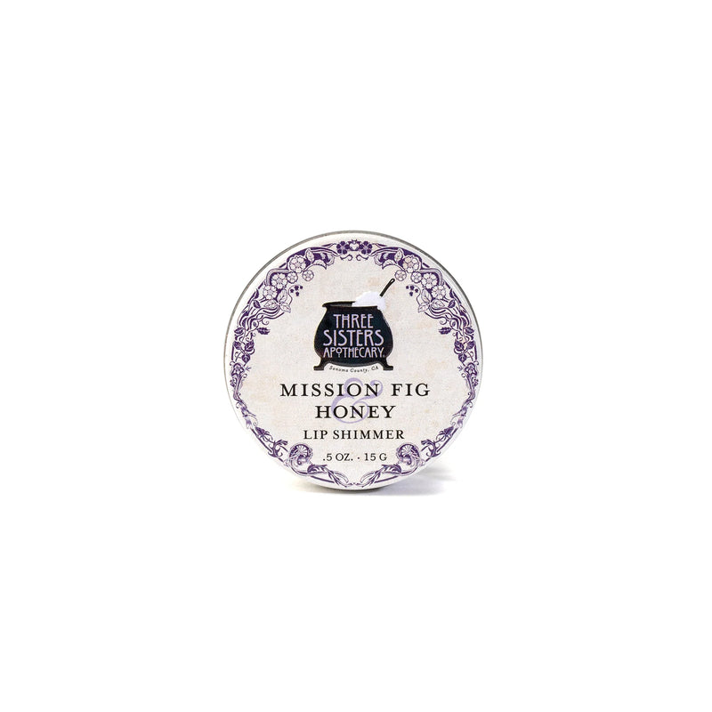 Three Sisters Apothecary California Mission Fig & Honey Lip Shimmer, 0.5 oz tin, features natural beeswax and a decorative purple border on white—ideal for hydrating lips.