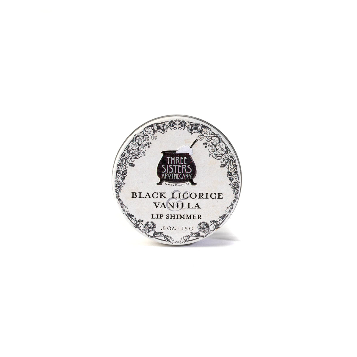 A round tin labeled "Three Sisters Aphothecary Black Licorice & Vanilla Lip Soother, 0.5 oz, 15 g" features floral designs on white. This hydrating balm is made with natural beeswax for soothing care.