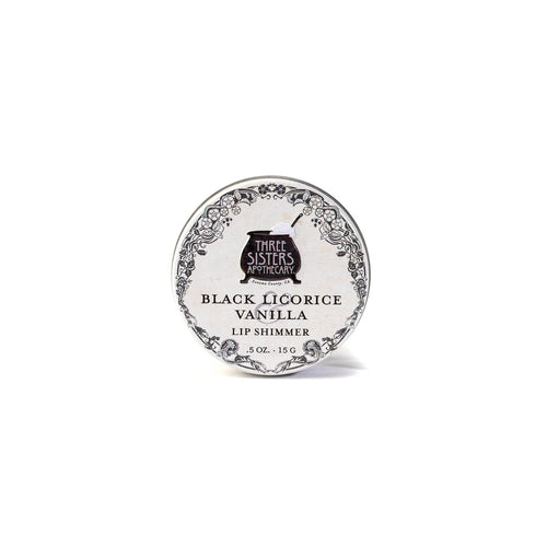 A round tin labeled "Three Sisters Aphothecary Black Licorice & Vanilla Lip Soother, 0.5 oz, 15 g" features floral designs on white. This hydrating balm is made with natural beeswax for soothing care.