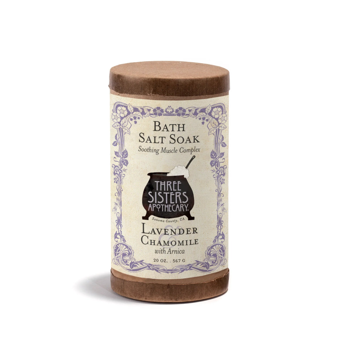A vintage-style cylindrical container of Three Sisters Apothecary Lavender & Chamomile Bath Salt Soak with Arnica features soothing Epsom salts and a floral label, offering a relaxing bath experience.