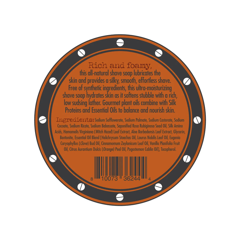 A circular label for the Three Sisters Apothecary Shave Soap - Bay Rum infused with Bay Rum essential oil. The orange label has a brown border adorned with small white circles. It describes the product as rich and foamy, listing ingredients such as nourishing natural oils and extracts. A barcode is positioned at the bottom.