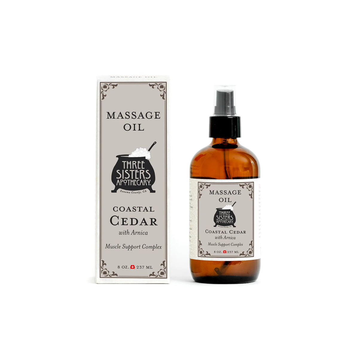An 8 oz (237 ml) brown bottle of Three Sisters Apothecary Coastal Cedar with Arnica Therapeutic Massage Oil, labeled for muscle relief, stands by its matching box—both botanical skincare products from Three Sisters Apothecary.