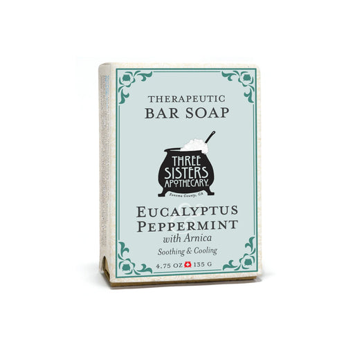 A rectangular box of Three Sisters Apothecary Eucalyptus & Peppermint Therapeutic Bar Soap features white packaging with teal accents and vintage-style text. This natural botanical bar soap weighs 4.75 oz (135 g).