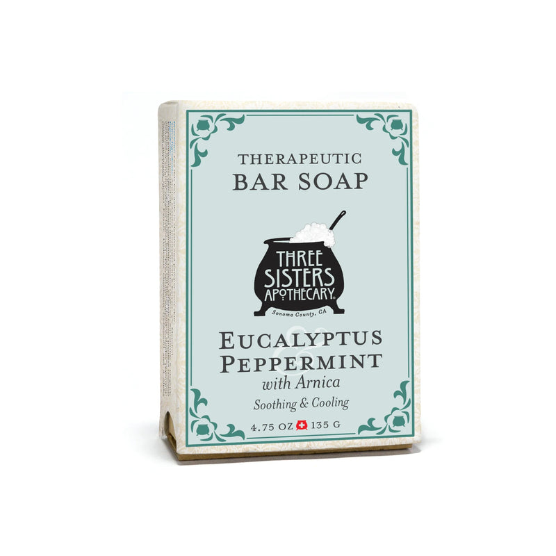 A rectangular box of Three Sisters Apothecary Eucalyptus & Peppermint Therapeutic Bar Soap features white packaging with teal accents and vintage-style text. This natural botanical bar soap weighs 4.75 oz (135 g).