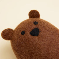 A close-up of the MODERNBEAST Wool Brown Bear Dog Toy, featuring soft brown wool, small round ears, and simple black-stitched nose and eyes, displayed against a plain light background.