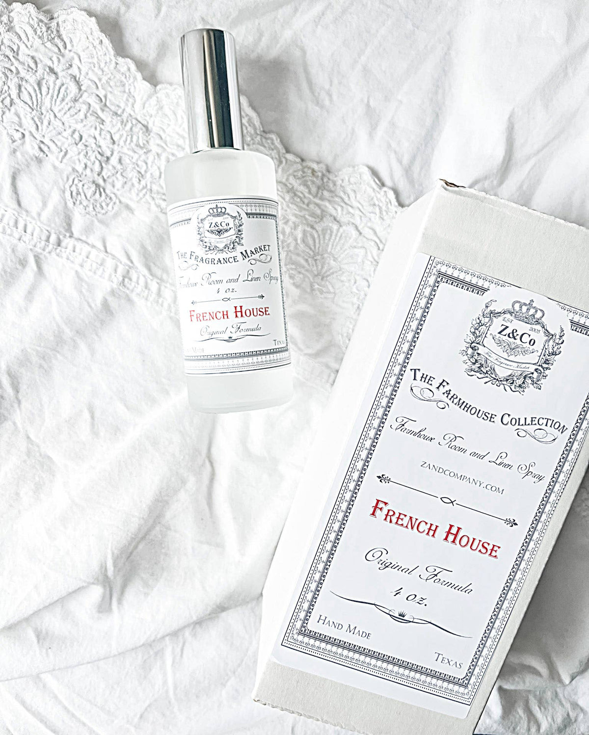 A clear spray bottle labeled "Z&Co. Salt Farmhouse Room/Linen Spray" by Z&Co. rests on white lace beside its matching box, both featuring the Z&Co. brand—an elegant, handcrafted Texas room spray that adds a charming farmhouse touch.