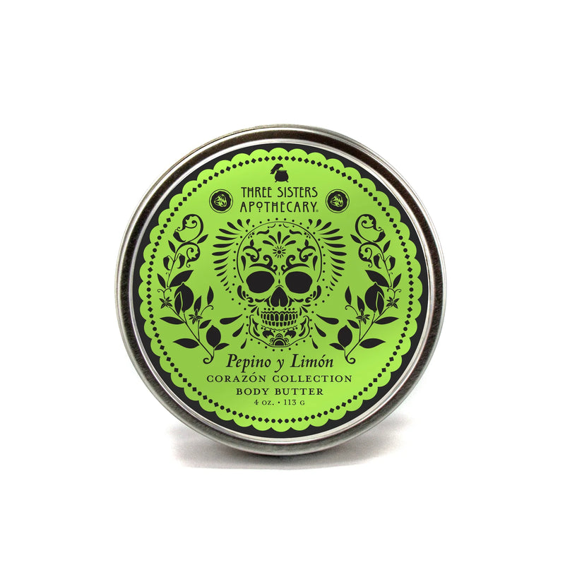 A round tin of Three Sisters Apothecary Pepino y Limón Body Butter from the Corazón Collection, featuring a green label with a sugar skull, floral designs, and providing natural hydration.