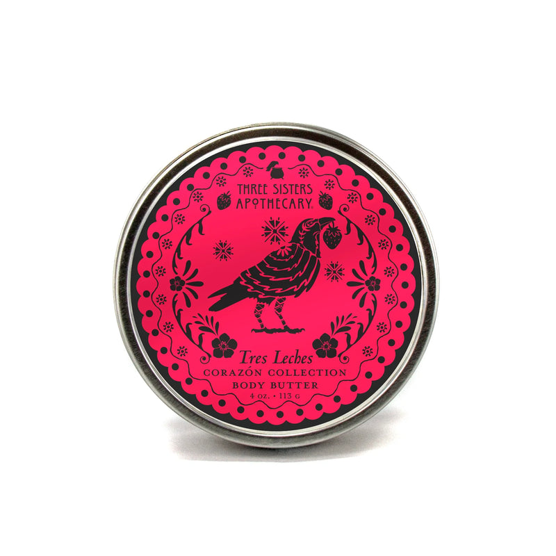A 4 oz (113 g) round tin of Three Sisters Apothecary Tres Leches Body Butter – Corazón Collection features a black bird and floral design on bright pink. This natural product is from Three Sisters Aphothecary.