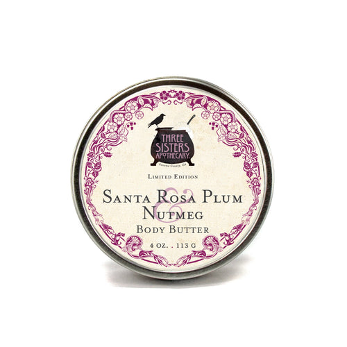 A 4 oz. round tin of Three Sisters Apothecary Santa Rosa Plum & Nutmeg Body Butter features a vintage-style label with a purple border and is enriched with shea butter for rich, natural moisture.