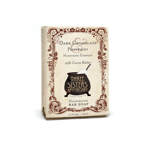 A rectangular box of Three Sisters Apothecary Dark Chocolate & Mint Bar Soap. The soap, weighing 4.75 ounces (135 grams), is labeled "Dark Chocolate Peppermint Nurturing Complex with Cocoa Butter" and contains peppermint essential oil. Its label features vintage-style floral designs and a cauldron illustration.