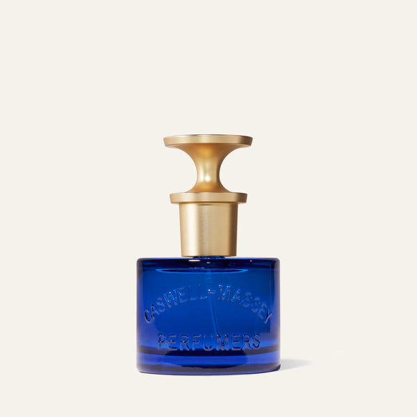 The Caswell-Massey Elixir of Love Eau de Toilette comes in a cobalt blue glass bottle with "CASWELL-MASSEY PERFUMERS" embossed on it and a gold T-shaped cap, pictured against an off-white background.