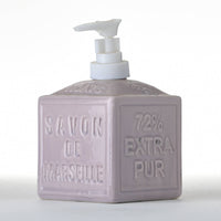 The French Soaps Liquid Soap Dispenser Savon de Marseille by FRENCH SOAPS is a square ceramic dispenser in lavender that features a pump on top. The front side proudly displays "Savon de Marseille" and "72% Extra Pur" embossed on it. With its minimalist design and traditional vintage feel, it's both functional and stylish.