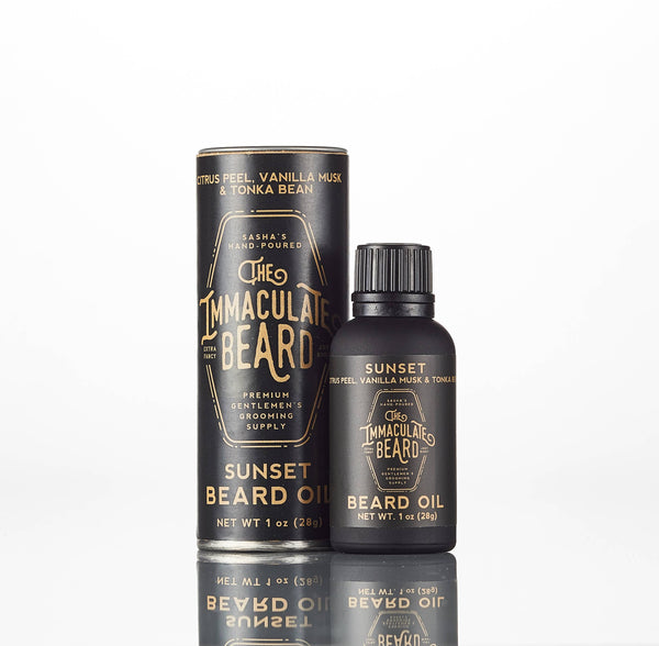 A bottle and cylindrical container of The Immaculate Beard SUNSET Cologne Oil, featuring black and gold packaging with notes of citrus peel, vanilla tonka bean, and premium grooming supply from The Immaculate Beard.