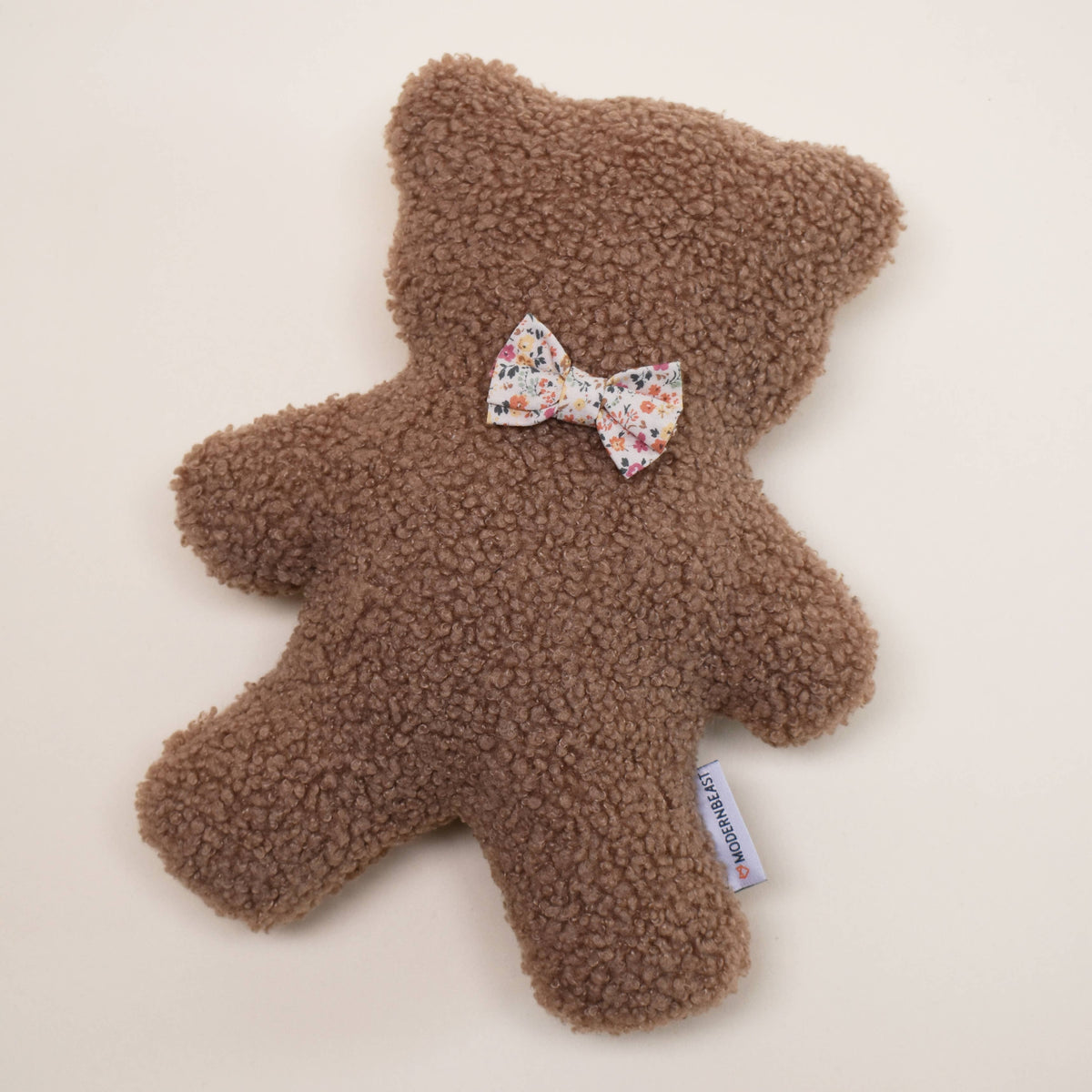 The MODERNBEAST Modernbeast Lavender Teddy Bear with Bowties is a soft, textured plush toy featuring a floral bowtie and white tag—perfect as a soothing bedtime companion for peaceful nights.