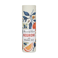 Stewart & Claire Negroni Lip Balm in a paper tube, made with organic oils and adorned with a vibrant botanical and citrus design on white—ideal for eco-friendly lip care.