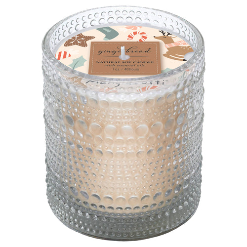 The Boston International Mangiacotti Gingerbread Soy Candle (7 oz) comes in a textured glass jar with a festive gingerbread-themed label—ideal for adding cozy holiday charm to any room.