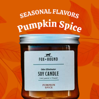 A Fox + Hound Odor Eliminator Soy Candle in Pumpkin Spice sits before an orange, leaf-patterned background. Above, “SEASONAL FLAVORS Pumpkin Spice” highlights this cozy candle from Fox + Hound.