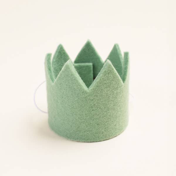 The MODERNBEAST Wool Pet Party Crown by MODERNBEAST is a small, light green felt crown with pointed tips and an elastic band, ideal as a dog birthday accessory. Shown on a plain off-white background.