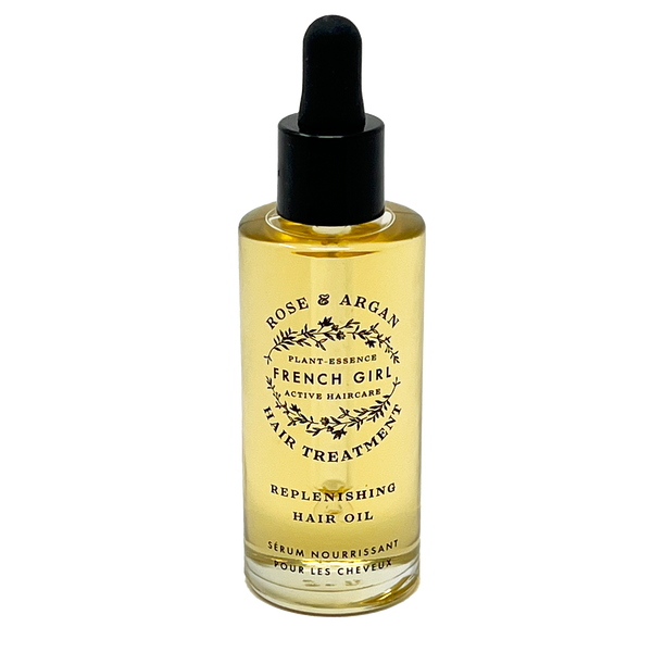 A clear glass dropper bottle of FRENCH GIRL Organic, Hydrating Rose Hair Treatment Oil (2 oz) filled with yellow oil is set against a black background.
