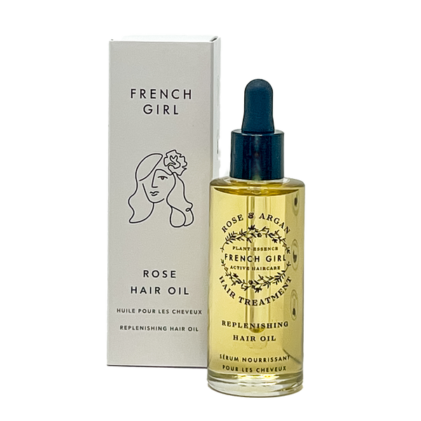 A glass dropper bottle of FRENCH GIRL Organic, Hydrating Rose Hair Treatment Oil (2 oz) with light yellow oil and a black dropper cap sits in front of its white box featuring a simple line drawing of a woman’s face and hair.