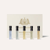Five small men’s fragrance vials from the Caswell-Massey Fragrance Discovery Collection stand before an off-white, gold-detailed Caswell-Massey box. Each vial features a unique scent from this renowned collection.