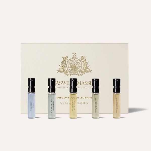 Five small men’s fragrance vials from the Caswell-Massey Fragrance Discovery Collection stand before an off-white, gold-detailed Caswell-Massey box. Each vial features a unique scent from this renowned collection.