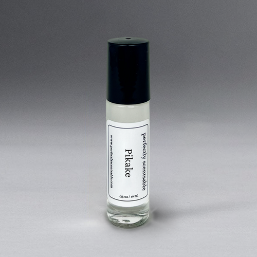 The Perfectly Scentsable Pikake Perfume Oil - Rollerball is a small 0.35 oz (10 ml) bottle with a black cap, offering a jasmine blend reminiscent of a tropical paradise. The label, set against a gradient from light to dark gray, includes the URL "www.perfectlyscentsable.com.