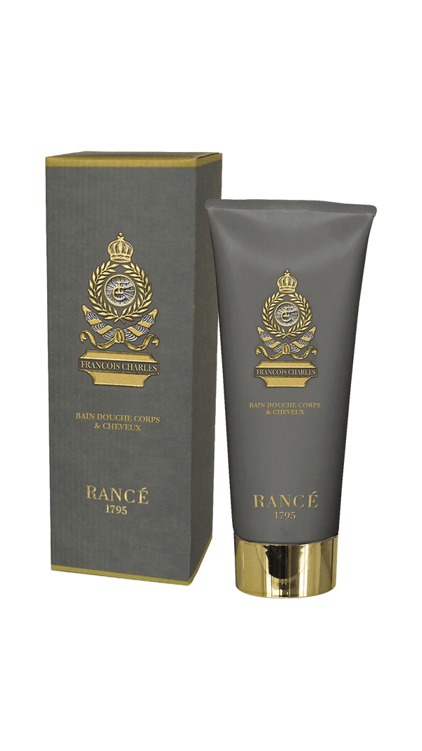 A gray tube and matching box of Rancé Francois Charles Body & Hair Shower Gel 200ml, both with gold emblem and text, reflect the brand's refined style and the product’s distinctive woody aroma.