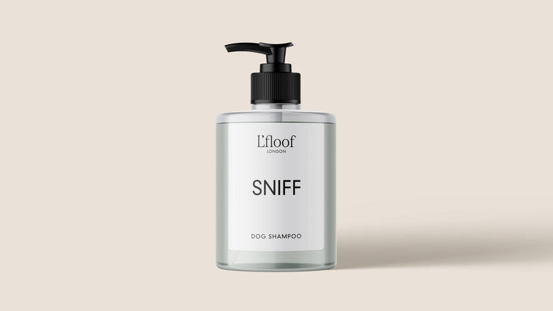 A bottle of L'floof cruelty-free dog shampoo featuring a pump dispenser. The label reads "L'floof SNIFF, Natural Oat & Aloe Dog Shampoo." The transparent bottle shows an off-white liquid inside, set against a light beige background, ideal for soothing irritated skin.