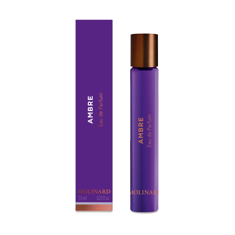 The Molinard Ambre Eau de Parfum Roll-On features a purple box and matching cylindrical bottle with copper accents and metallic cap, offering 7.5 ml (0.25 fl oz) of fragrance by Molinard.