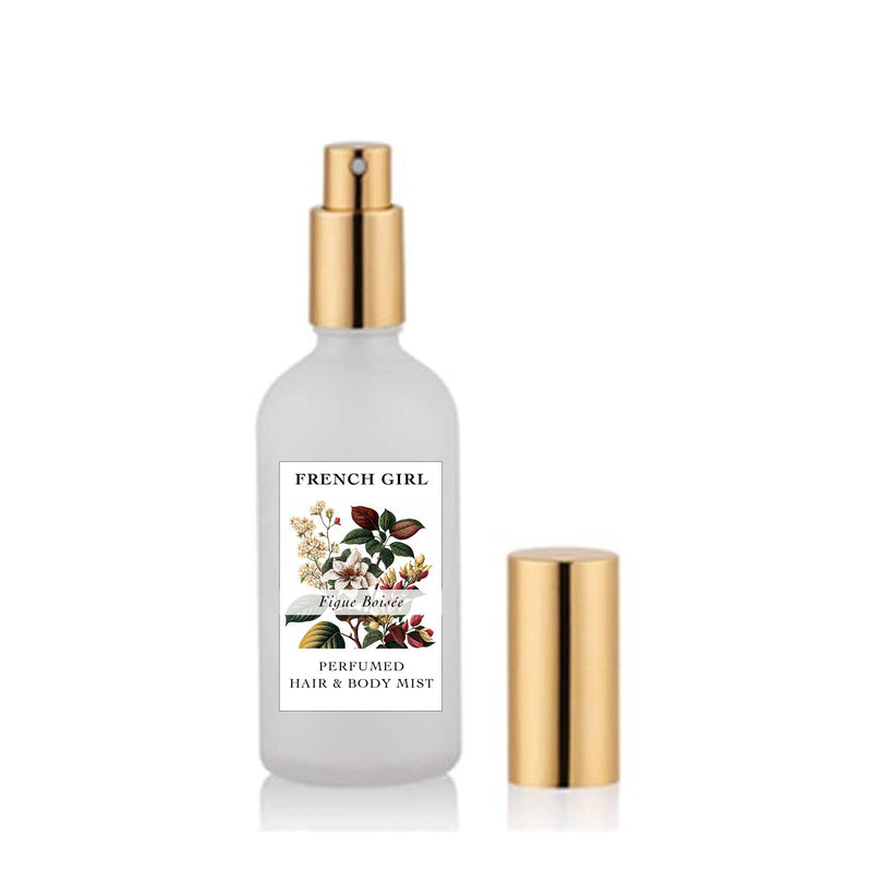 A frosted glass spray bottle, labeled "FRENCH GIRL Perfumed Hair & Body Mist Alcohol-Free Vegan - 3 Scents," features a floral design and gold spray top, with a matching gold cap beside it.